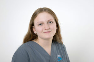 Hannah Jeromin mit langen braunen Haaren, lächelt leicht und trägt graublaue Kleidung