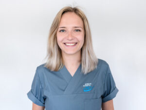 Lara Clausen-Stuck mit schulterlangen blonden Haaren, lächelt und trägt graublaue Kleidung